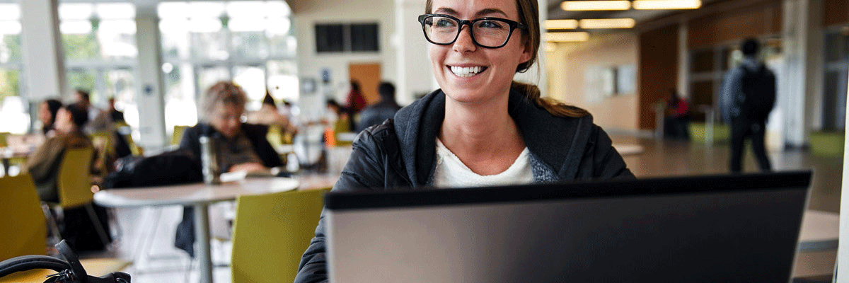 Student smiles while studying on the computer in the library