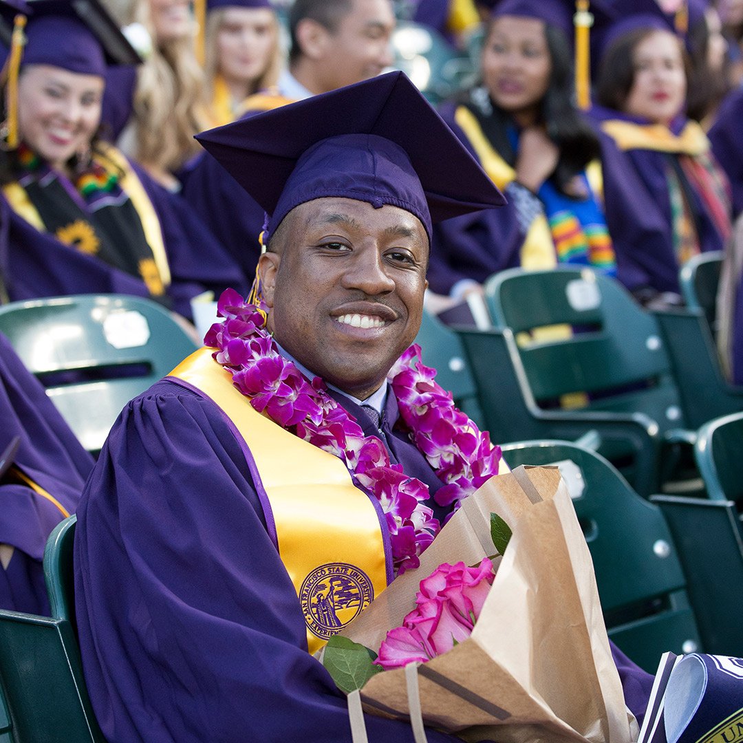 Graduate in flower lei, holding a bouquet