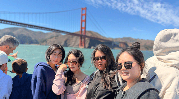 International students on a bay cruise with the Golden Gate Bridge behind them