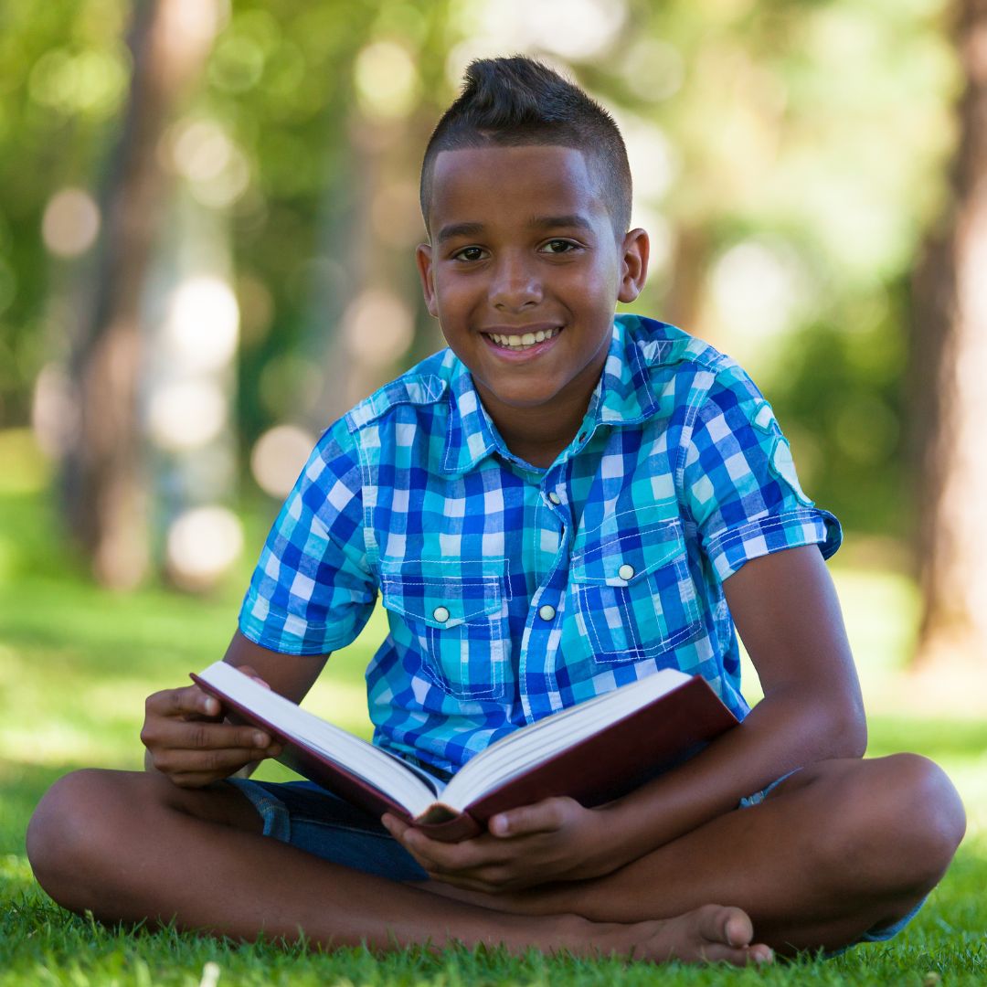 Boy reading a book outside