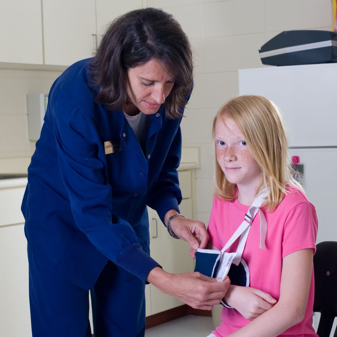 School nurse puts girl's arm in a sling