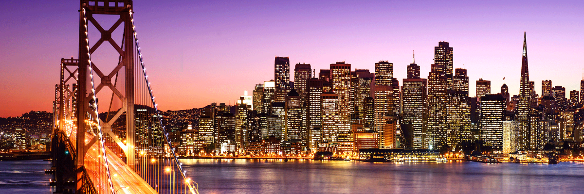 A iew of the Bay Bridge and Downtown San Francisco with a purple sunset