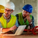 Construction project coordinators and project manager at a construction site with a computer