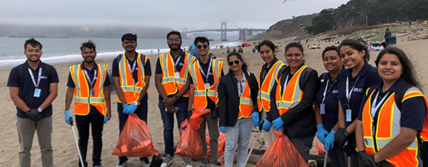 International student cleanup volunteers on a foggy beach with the Golden Gate Bridge behind them in the distance