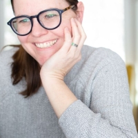 Instructional designer taking an online course, smiles while looking at laptop