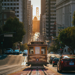 San Francisco cable car on a hill with the Bay Bridge in the background