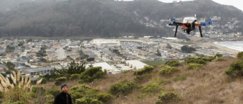 GIS student works with a drone on a hill