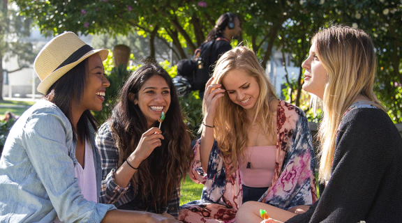 A group of women sit on the SF State campus lawn